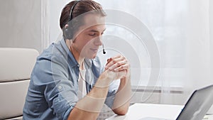 Workplace of freelancer. Employee works at home office using computer and headset. Young man is having a conference call