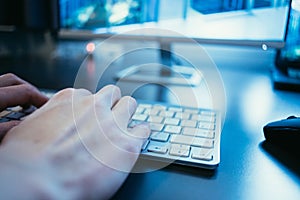 Workplace of a freelancer: Typing hands, screen in the blurry background