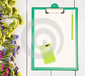 Workplace with green clipboard, blank yellow paper, calculator,