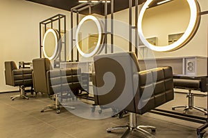 Workplace of the hairdressers with illuminated mirrors and comfortable chairs