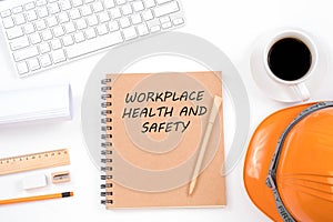 Workplace health and safety concept. Top viwe of modern workplace with safety helmet, office supplies, a cup of coffee and