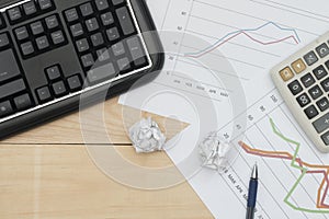 Workplace with keyboard, graph, calculator, and pan on wood table