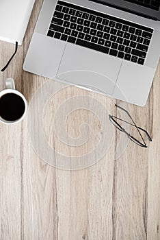 Workplace - laptop computer, coffee and eyeglasses at office desk with wooden copy space.
