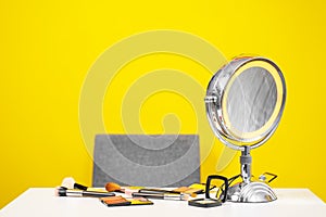 Workplace of makeup artist or beauty blogger on yellow background, copy space. Tools are on table - brushes and palettes