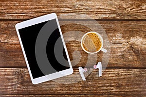 Workplace with modern gadgets white digital tablet coffee cup of espresso on wireless headphones with wooden table