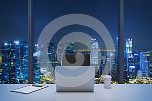 A workplace in a modern panoramic office with New York evening view. A white table, black leather chair.