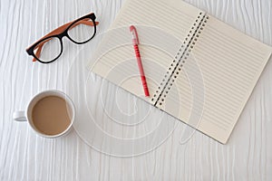 Workplace with note, paper, pen and cup of coffee on work table. Top view shot