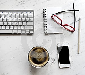 Workplace with notebook, coffee, smartphone, glasses and keyboard.