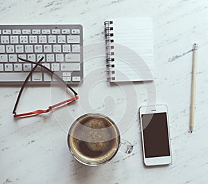 Workplace with notebook, coffee, smartphone, glasses and keyboard.