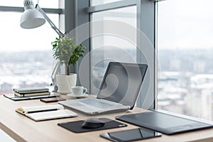 Workplace with notebook laptop Comfortable work table in office windows and city view.