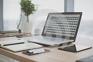 Workplace with notebook laptop Comfortable work table in office windows and city view.