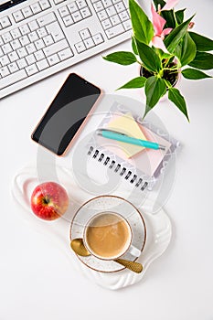 Workplace and office desk with coffee, apple, laptop, headset and smarthpone