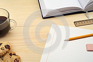 Workplace, office supplies, coffee cup and cookies on wooden table.