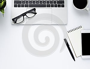 Workplace in office with white desk. Top view from above of laptop with notebook and coffee.