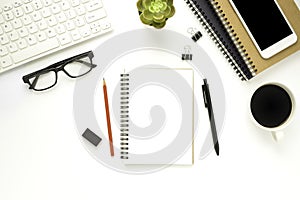 Workplace in the office with a white desk. Top view from above of laptop with notebook and pen. Space for modern creative work of