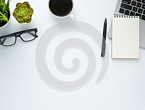 Workplace in office with white desk. Top view from above of laptop with notepad and coffee. Space for modern creative work of desi