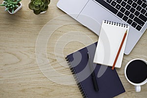 Workplace in office with wood desk. Top view from above of laptop with notebook and coffee. Space for modern creative work of a de