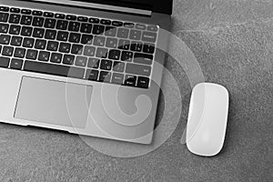 Workplace with open laptop with black screen and mouse on modern grey stone desk, filtered image, focus on keyboard.Office table