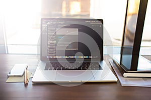 Workplace with open pc laptop computer with web site and programs on screen lying on wooden table