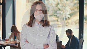 Workplace safety measures. Portrait of young happy gen-z 20s business woman wear mask at modern light office slow motion