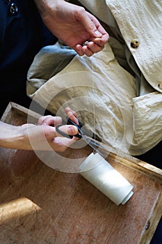 Workplace of seamstress. Dressmaker cuts dress detail, sew on buttons, spools of thread, tailor shop, tailoring, close up