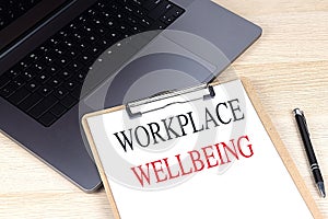 WORKPLACE WELLBEING text on clipboard on laptop