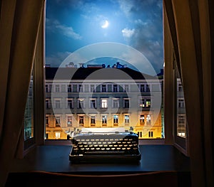 Workplace of a writer, journalist, creator. Old typewriter on the table against the background of ancient night city buildings.