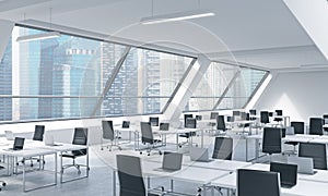 Workplaces in a bright modern open space loft office. White tables equipped by modern laptops and black chairs.