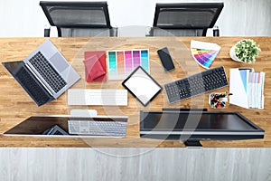 Workplaces in office table chairs tablet smartphone color palette pencils tablet keyboard monitors.