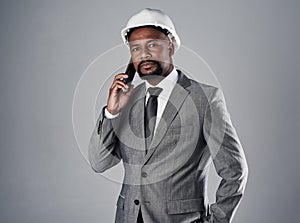 He works as hard as his team. Portrait of a well-dressed civil engineer using his cellphone while standing in the studio