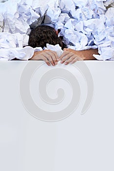 Works got him pinned down. a businessman buried under a pile of crumpled up paperwork.