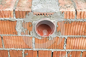 Works on the laying of ceramic bricks. Red brick wall with ventilation hole. Embedded detail in the wall. Progressive construction