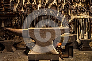 Workshop, metal tools and anvil in forge with wall background for industry, manufacturing or development. Retro factory