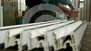 Workshop for the production of PVC windows, the male worker twists the in the PVC profile for further assembly of