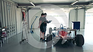 Workshop with two specialists talking about their racing car