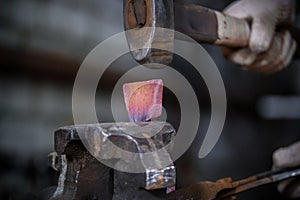 Workspace of blacksmith. Blacksmith working with red hot metal workpiece of new hammer in the vise at the forge