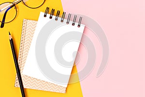 Workspace with blank notepad mockup, eyeglasses and stationery.