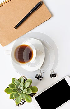 Workspace compositon  with, coffee cup,notebook,pen ,csmart phone and green leaves pot with space on white background,flat lay