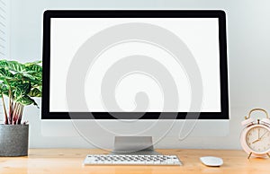 Workspace with computer with blank white screen, and office supplies on a wooden desk