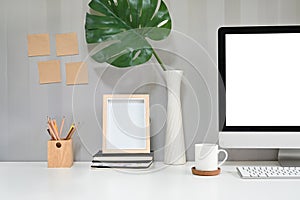 Workspace with computer, coffee mug, pencil and photo frame with sticky note on the wall