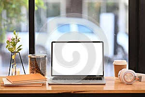 Workspace with computer laptop, headphone, coffee cup and books on wooden table.