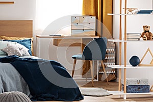 Workspace with desk and chair in elegant teenager`s room with blue and orange design