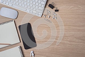 Workspace with diary or notebook and clipboard, mouse computer, keyboard, smart phone, Earphone, pencil, pen on wooden background