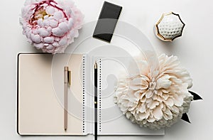 Workspace with diary notebook, gold accessories, blossom peony flowers. Bloom floral top table view for banner. Generative AI