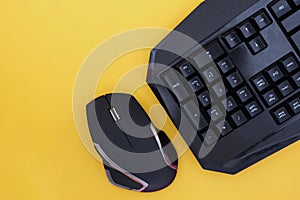 Workspace with a keyboard and mouse on a yellow background. Black mouse, keyboard isolated on a yellow background