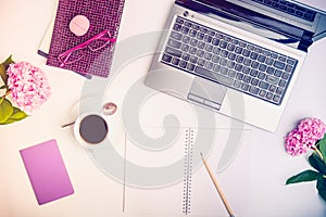 Workspace with laptop, notebook, sketchbook, glasses, cup of coffee and wisteria flowers on white background. Top view feminine of