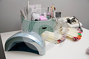 Workspace of a manicurist with tools, pallets, tongs, nail polishes, nail files and a lam