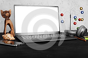 Workspace: modern laptop computer blank isolated white screen, mobile smartphone, headphones, pen, pencil, cat figurine, seashell