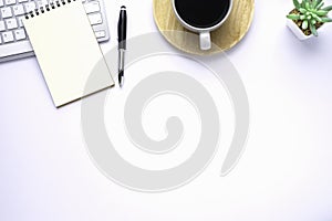 Workspace in office with white table. Top view from above of keyboard with notebook and coffee. Desk for modern creative work of d