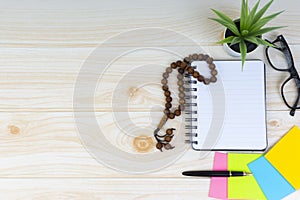 Workspace with Pen, spectacles, decoration flower, rosary and book.Copy Space